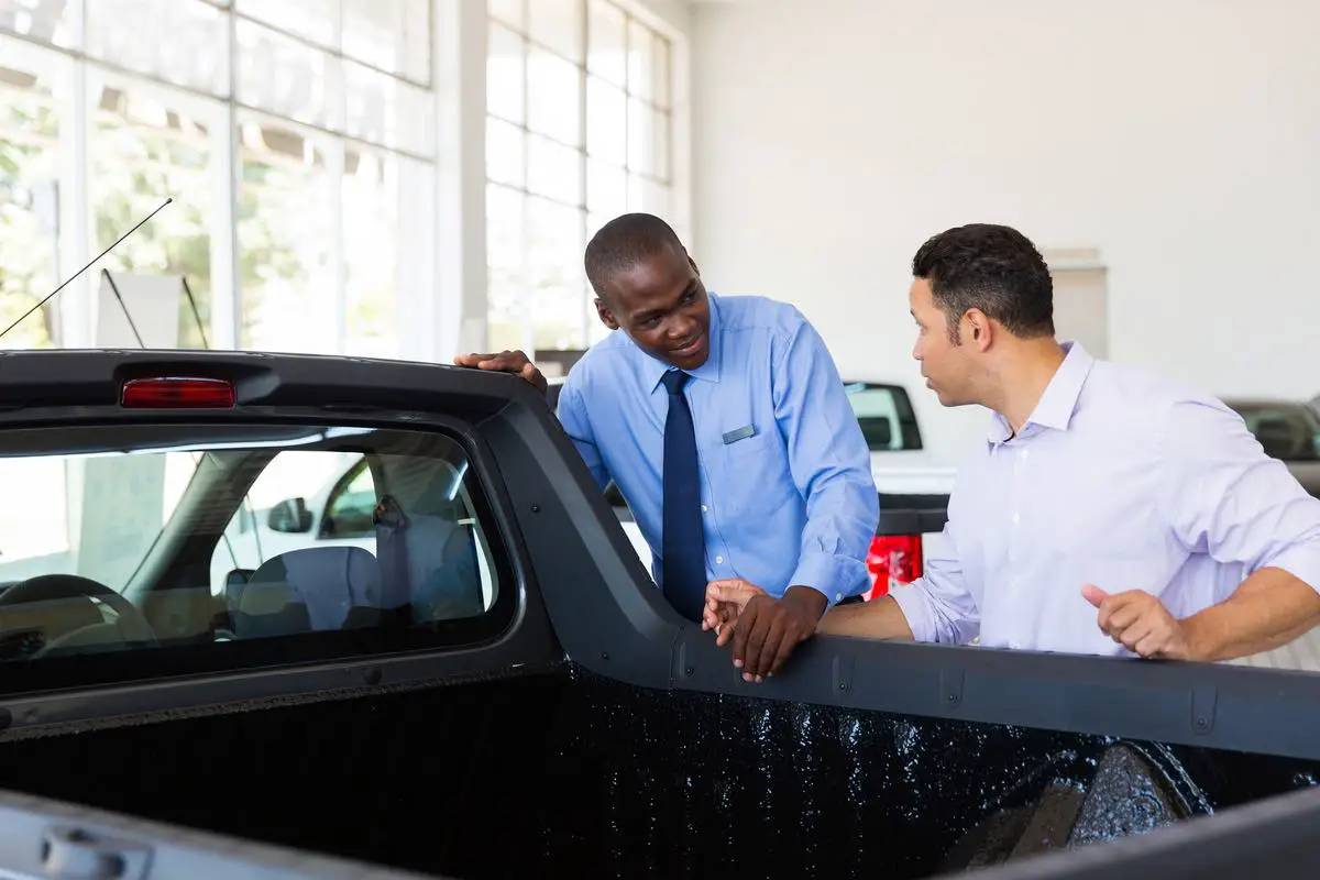 confident car salesman selling a car to middle aged customer