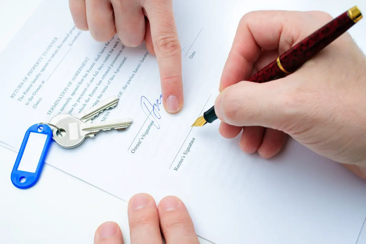 Rental agreement form with signing hand and keys and pen