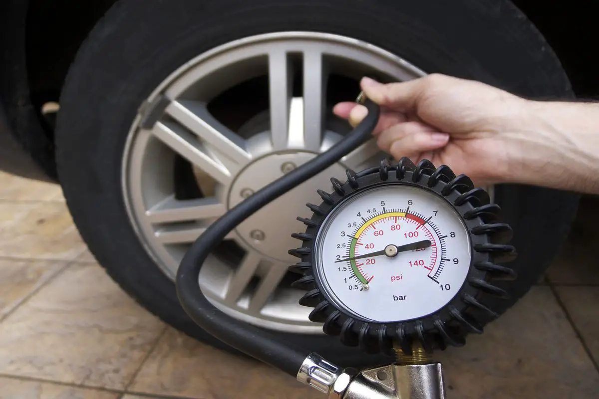 Close-up of manometer and man hands checking tyre pressure with gauge.